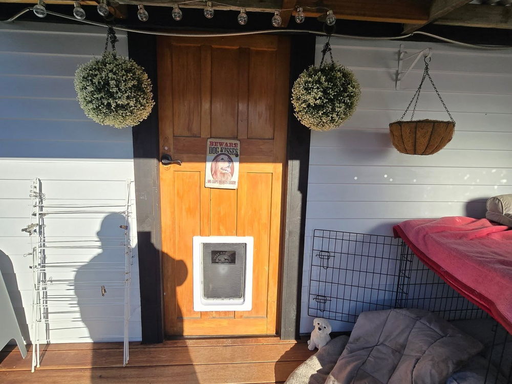 Covered timber deck with hanging planters under a corrugated iron roof