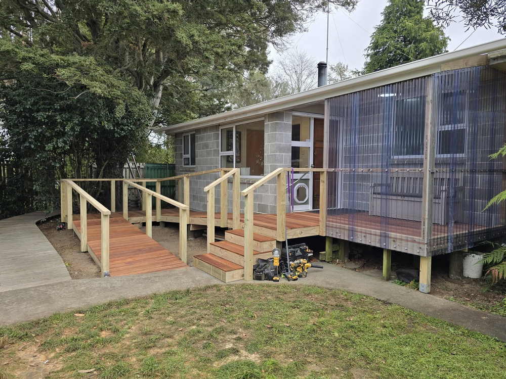 Timber deck with a handrail and an access ramp on the back of a concrete block house