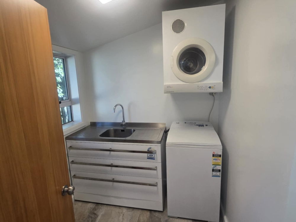 Compact laundry with a wall-mounted dryer, a stainless tub and drawers