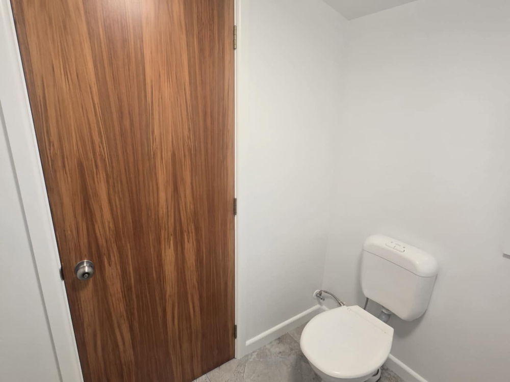 Separate toilet with a timber door and a large-format tiled floor