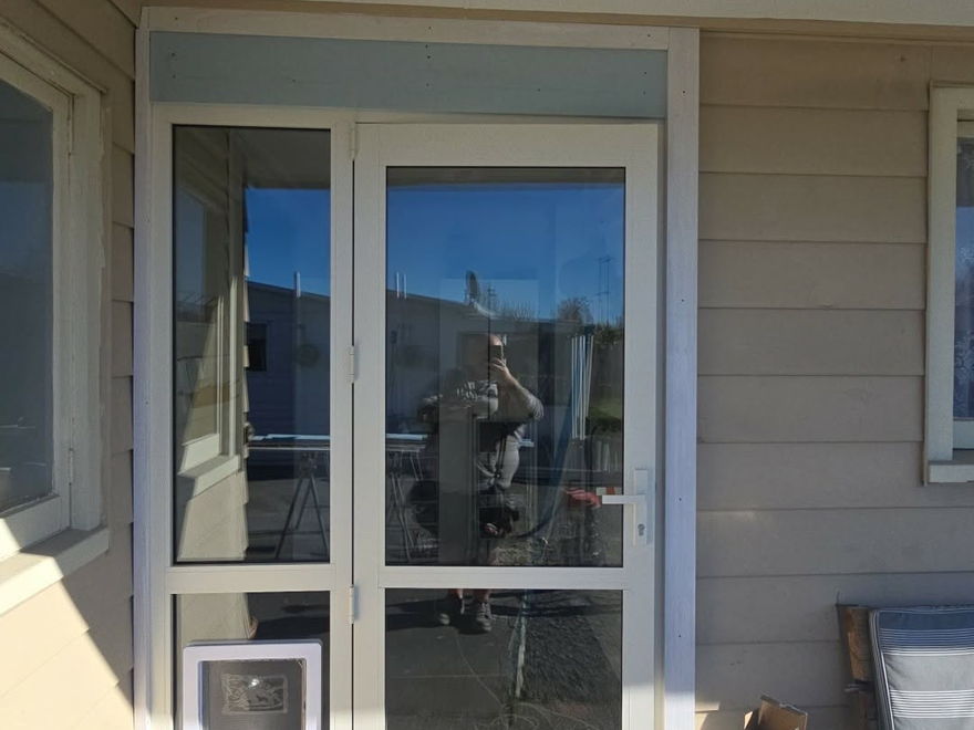 New white aluminium door with a built-in pet door fitted into the entry of a weatherboard house